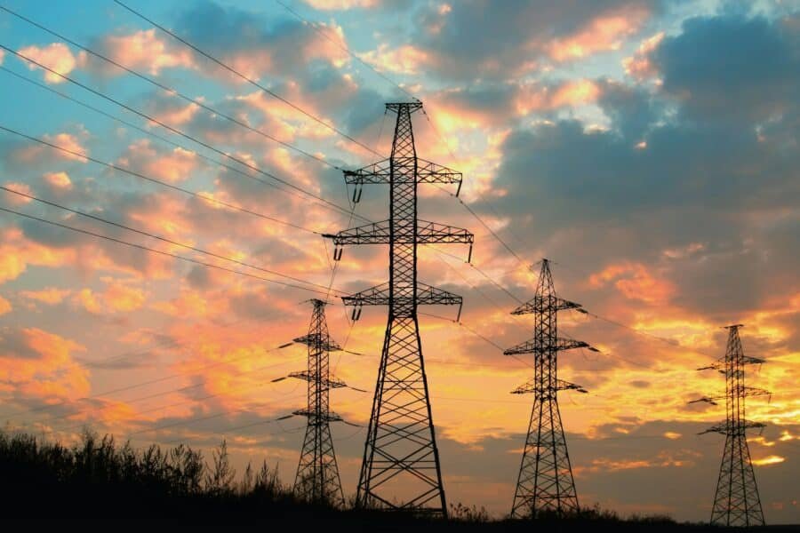 High voltage power transmission line. Silhouette electricity post on sunset background