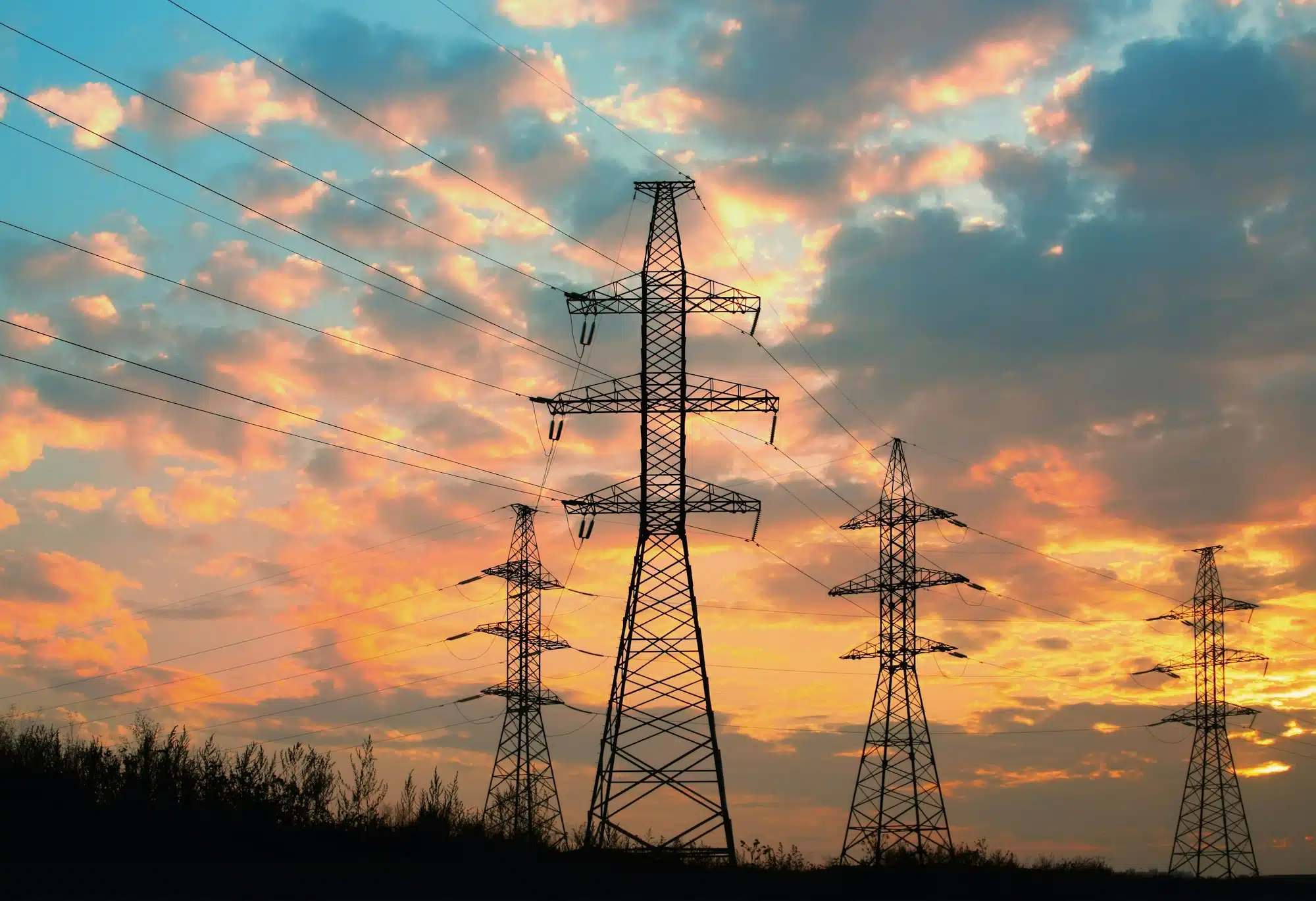 High voltage power transmission line. Silhouette electricity post on sunset background